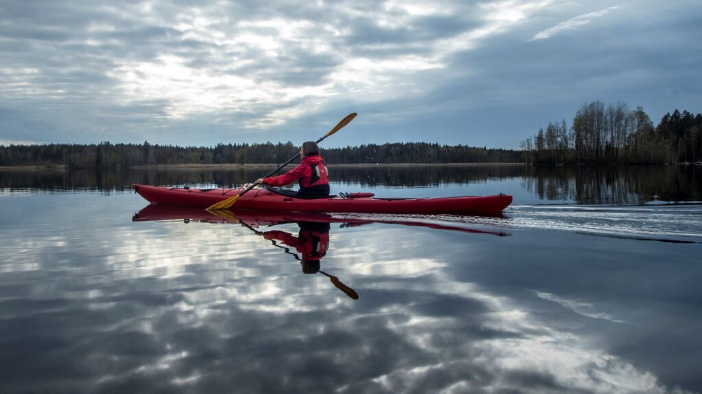 Kajakki, meloja ja pilvet, heijastuksia veden pinnassa Koskeljärvellä
